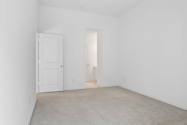 unfurnished room featuring baseboards and light carpet