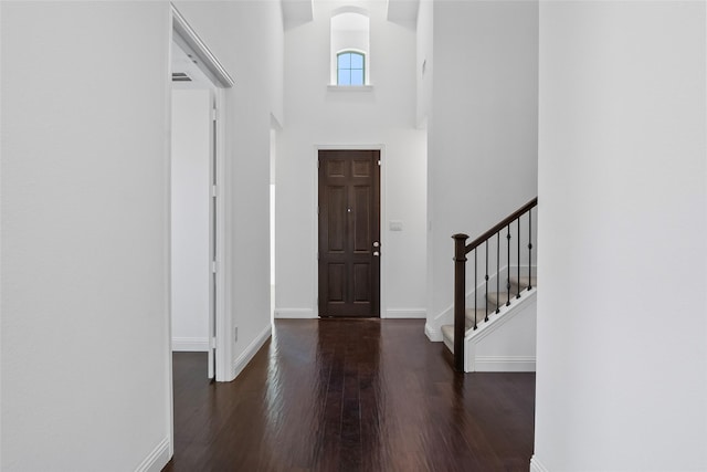 entrance foyer featuring visible vents, baseboards, stairs, a high ceiling, and wood finished floors