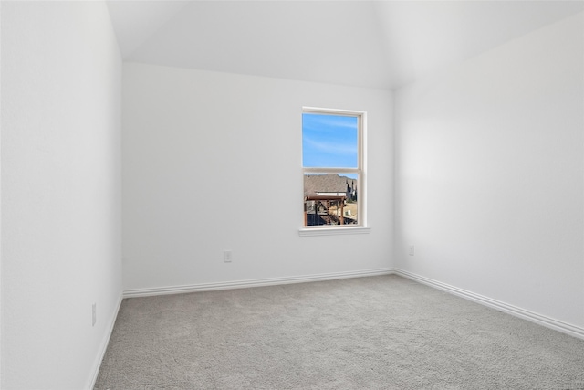 carpeted empty room with baseboards and vaulted ceiling