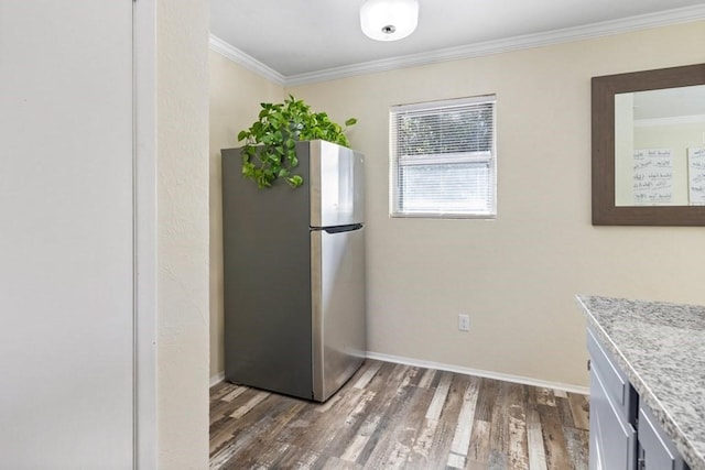 kitchen featuring freestanding refrigerator, light countertops, crown molding, and wood finished floors