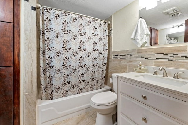 bathroom featuring vanity, shower / bath combo, a textured ceiling, visible vents, and tile walls