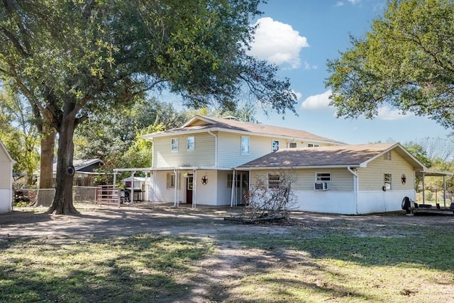 rear view of property featuring driveway, fence, and a lawn