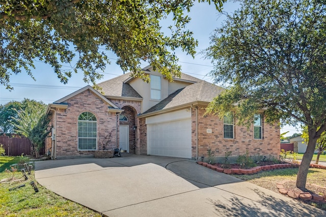 traditional home with fence, roof with shingles, concrete driveway, an attached garage, and brick siding