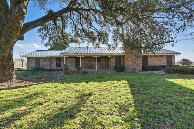 ranch-style home with metal roof, brick siding, a front lawn, and a standing seam roof