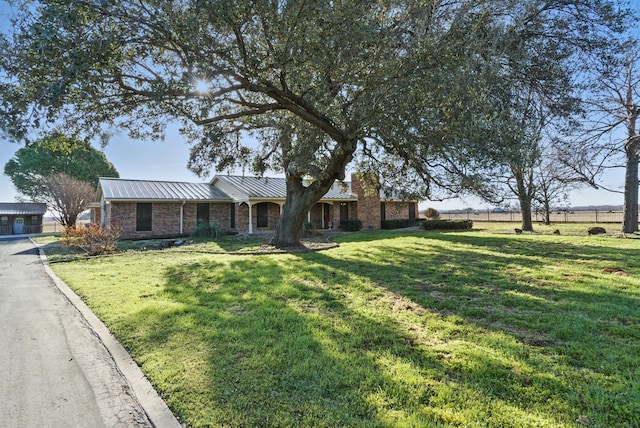 ranch-style house with a standing seam roof, a front yard, brick siding, and metal roof