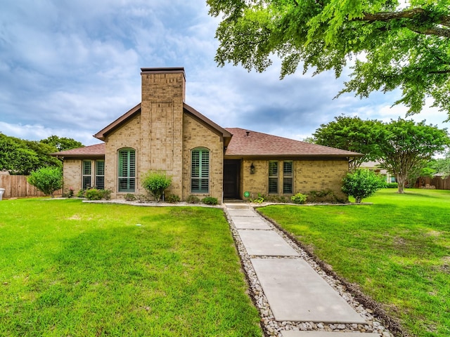 view of front facade featuring brick siding, a front lawn, and fence