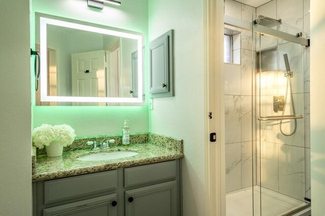 bathroom featuring a marble finish shower and vanity