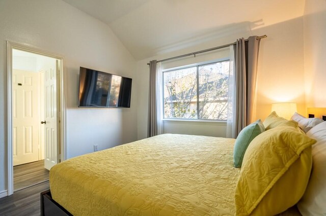 bedroom featuring dark wood-style flooring and vaulted ceiling