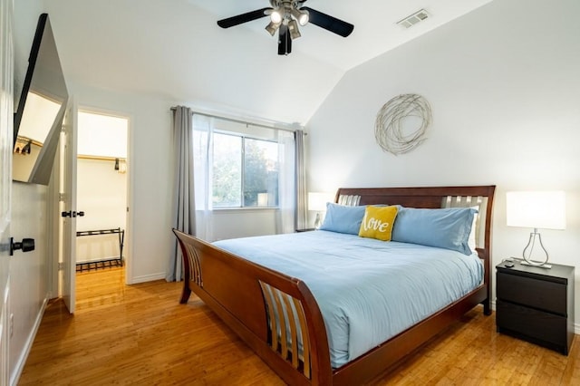 bedroom featuring visible vents, light wood-style floors, baseboards, ceiling fan, and vaulted ceiling