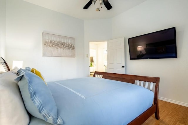 bedroom with a ceiling fan, wood finished floors, and baseboards