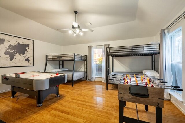 bedroom with baseboards, light wood-style flooring, and vaulted ceiling