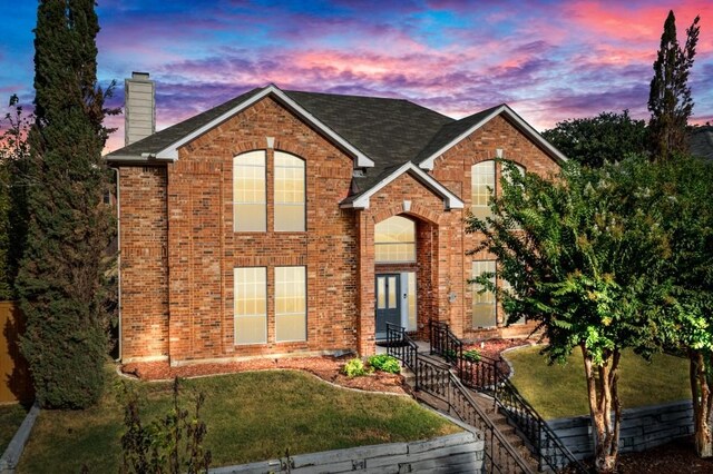 traditional-style home featuring a front yard, brick siding, and a chimney