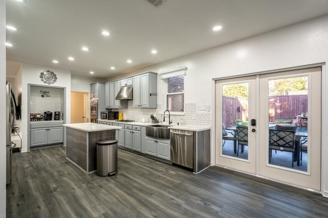 kitchen featuring gray cabinetry, under cabinet range hood, light countertops, stainless steel appliances, and a sink