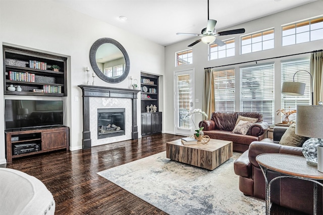 living room with ceiling fan, baseboards, wood finished floors, and a tiled fireplace