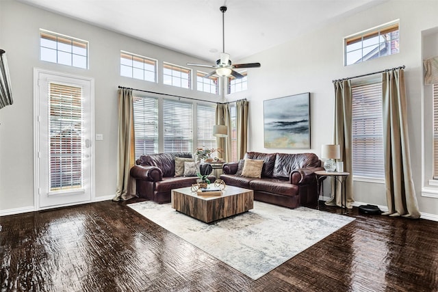 living room featuring a high ceiling, a healthy amount of sunlight, baseboards, and wood-type flooring