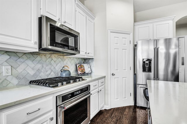 kitchen with light stone counters, backsplash, white cabinetry, and stainless steel appliances