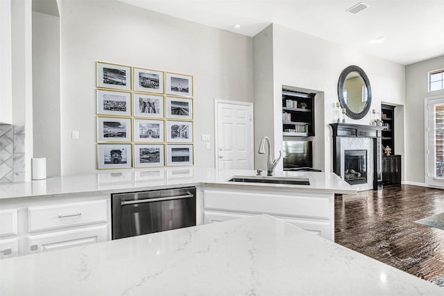 kitchen with visible vents, dishwasher, light stone counters, a fireplace, and a sink