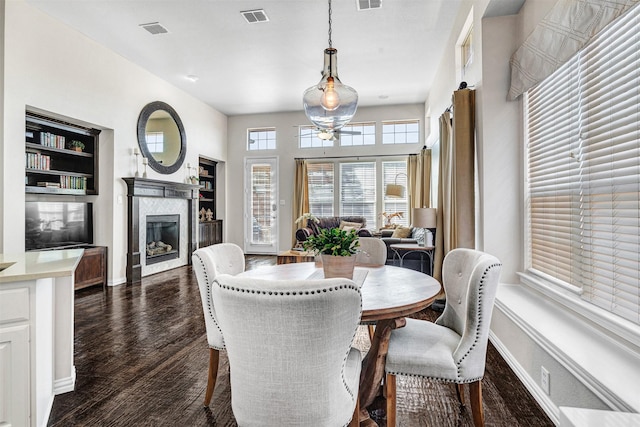 dining room with dark wood finished floors, visible vents, baseboards, and a premium fireplace