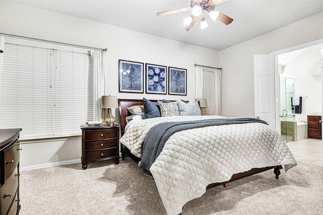 bedroom featuring baseboards, light carpet, a ceiling fan, and ensuite bathroom