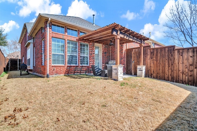 back of property featuring brick siding, roof with shingles, a yard, a fenced backyard, and a pergola