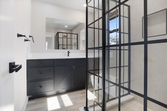 bathroom with recessed lighting, vanity, walk in shower, and wood finished floors