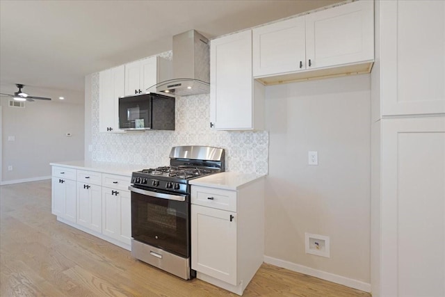 kitchen with visible vents, light wood-type flooring, gas range, wall chimney range hood, and tasteful backsplash