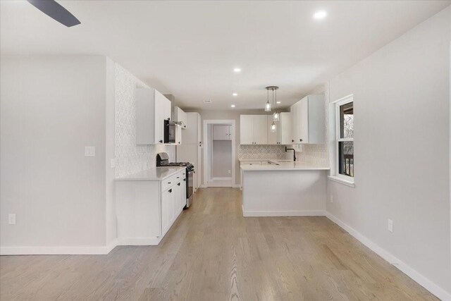 kitchen with stainless steel gas range oven, light wood finished floors, tasteful backsplash, light countertops, and baseboards