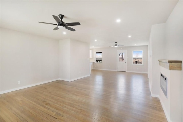 unfurnished living room with recessed lighting, baseboards, a fireplace, and light wood finished floors