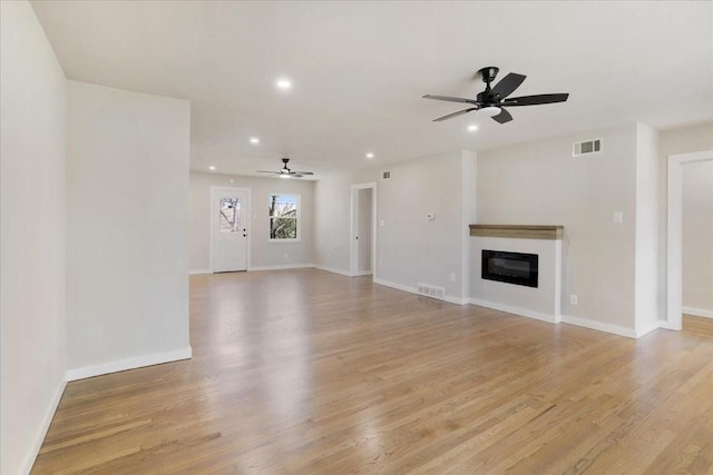 unfurnished living room with recessed lighting, visible vents, a glass covered fireplace, and light wood finished floors