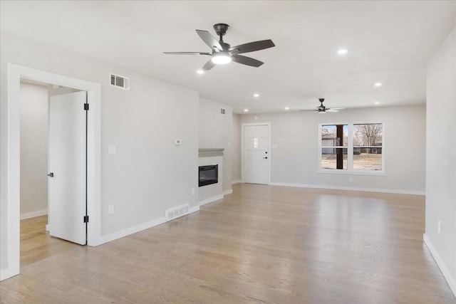 unfurnished living room featuring visible vents, recessed lighting, baseboards, and a glass covered fireplace