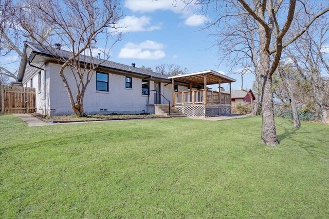 rear view of property with a lawn, fence, brick siding, and crawl space