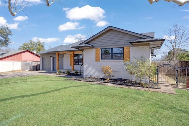 view of front of house featuring a front lawn, a gate, fence, a garage, and brick siding