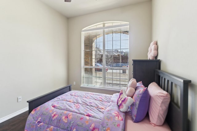 bedroom with a ceiling fan, wood finished floors, and baseboards