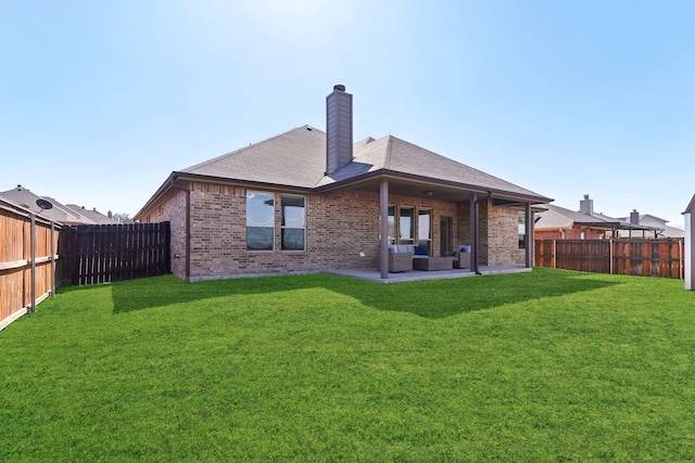 back of property featuring brick siding, a fenced backyard, a lawn, and a patio area