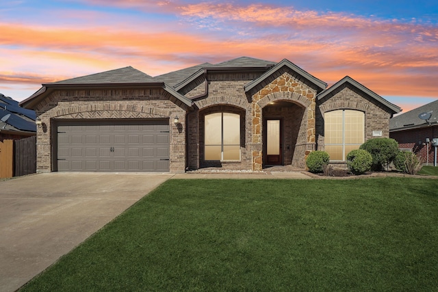 french country home featuring brick siding, a front lawn, roof with shingles, a garage, and driveway