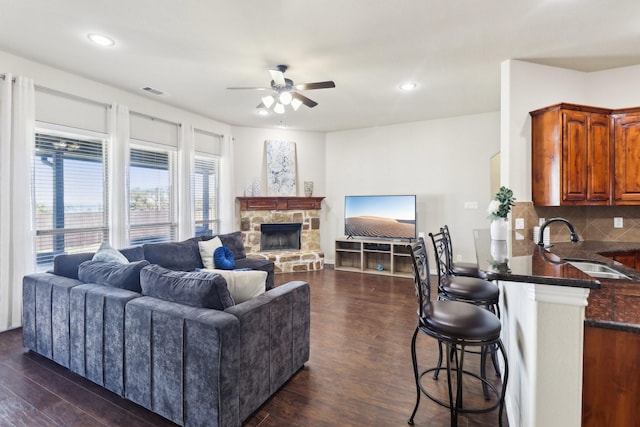 living room with visible vents, a ceiling fan, dark wood-style floors, recessed lighting, and a stone fireplace