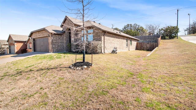 view of side of property featuring a garage, fence, brick siding, and a lawn