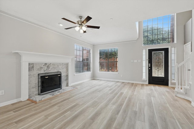 unfurnished living room featuring a fireplace, a ceiling fan, baseboards, and wood finished floors