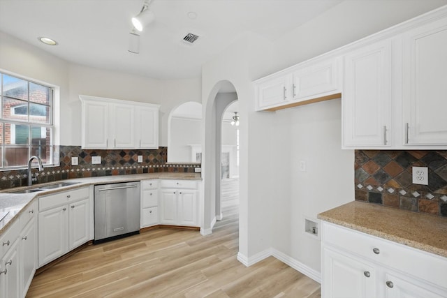 kitchen featuring stainless steel dishwasher, white cabinets, visible vents, and a sink