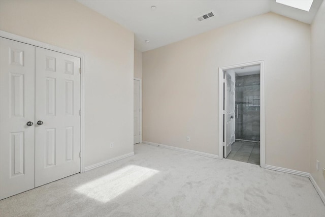 unfurnished bedroom with visible vents, baseboards, carpet, and vaulted ceiling with skylight