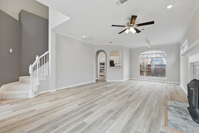 unfurnished living room with baseboards, stairway, light wood-type flooring, ornamental molding, and a fireplace