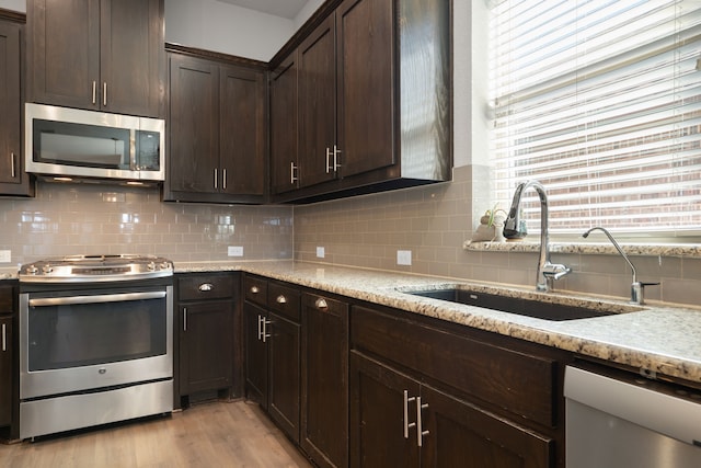 kitchen with a sink, stainless steel appliances, dark brown cabinets, and decorative backsplash