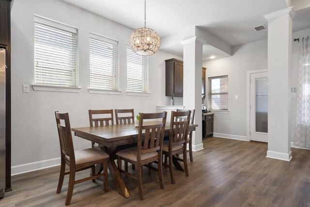 dining room with visible vents, wood finished floors, baseboards, and decorative columns