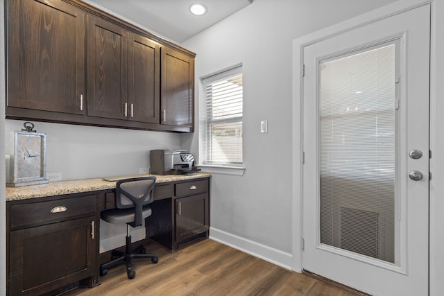 office space featuring built in study area, baseboards, and wood finished floors