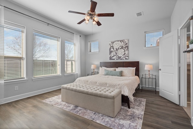 bedroom with dark wood-style floors, visible vents, multiple windows, and baseboards