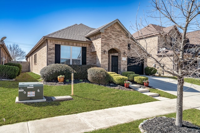 view of front of property featuring brick siding, concrete driveway, a front yard, and roof with shingles