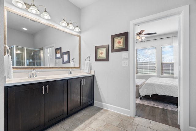 full bathroom with a stall shower, a sink, double vanity, baseboards, and ceiling fan