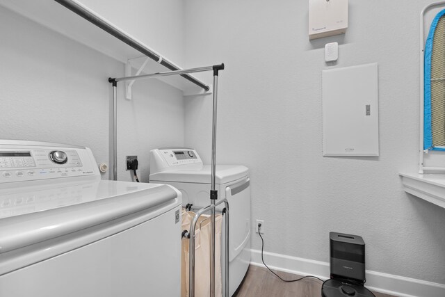 washroom featuring laundry area, washing machine and dryer, baseboards, and wood finished floors