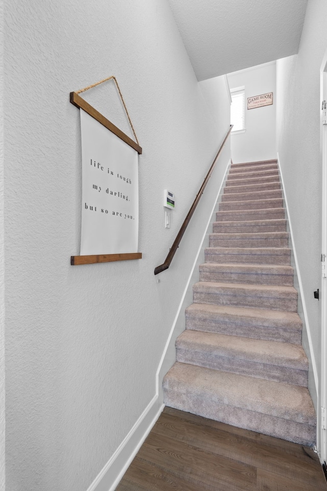 stairway with lofted ceiling, wood finished floors, and baseboards