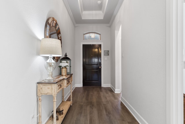 entryway featuring baseboards, dark wood finished floors, arched walkways, crown molding, and a raised ceiling